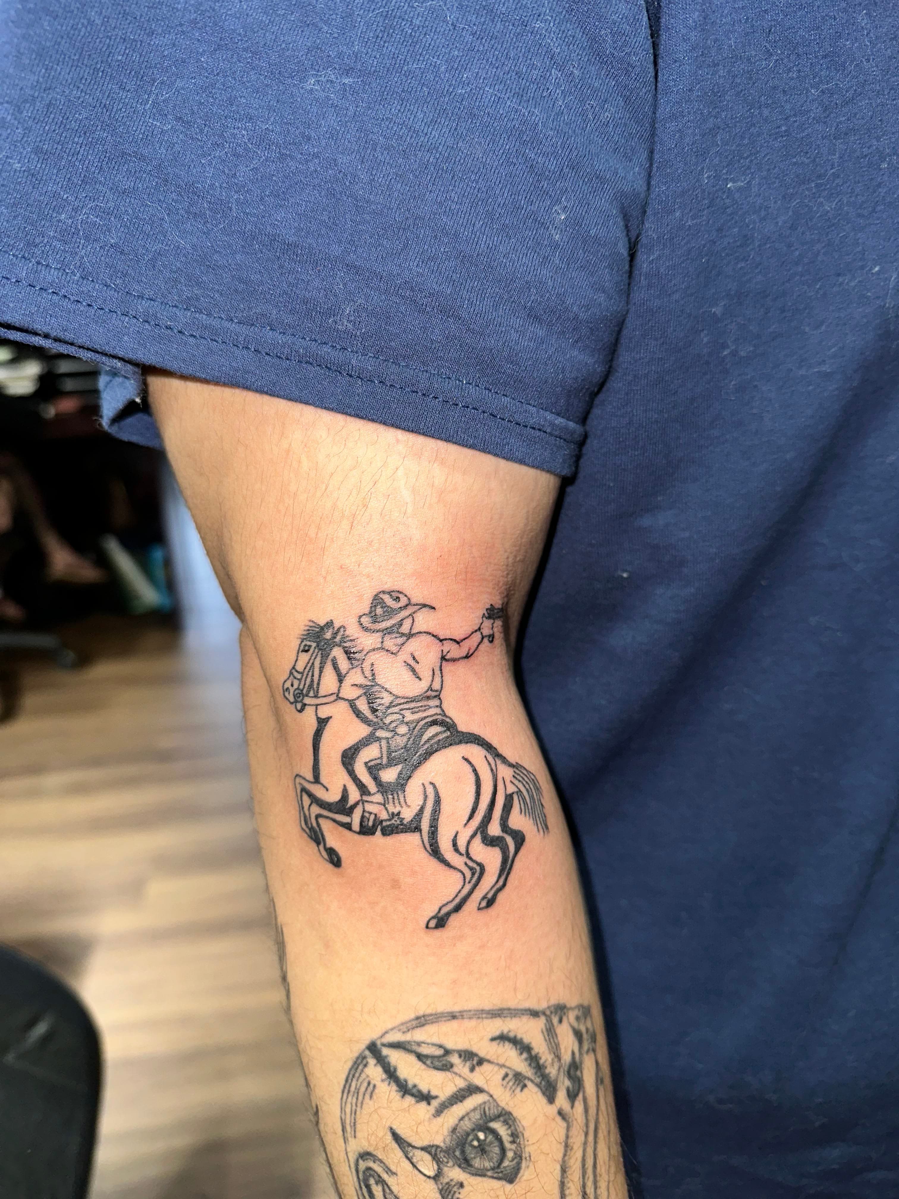 Old western cowboy shooting a gun on horseback tattoo